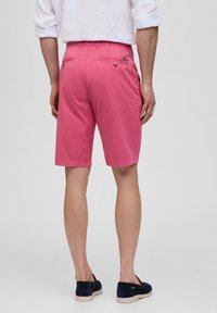 Roze katoenen shorts met een lengte tot halverwege de dijen, voorzien van een ontwerp met achterzak en een platte voorkant, gecombineerd met donkere instappers.