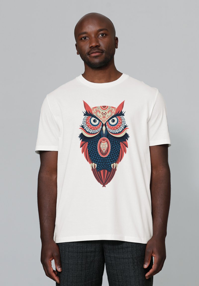 Weißes Baumwoll-T-Shirt mit einem farbenfrohen Eulendesign, das detaillierte Elemente in Rot, Blau und Schwarz aufweist. Kurze Ärmel und runder Halsausschnitt.