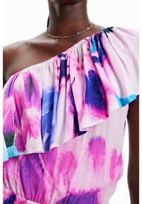 Vestido de un solo hombro en tejido ligero y fluido con un patrón floral en tonos rosa, púrpura y azul, con un acento de volantes en la parte superior.