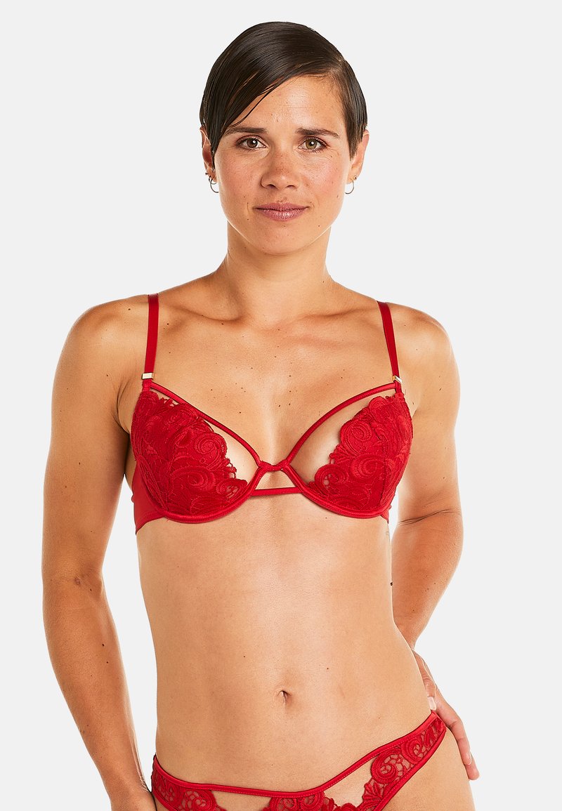 Soutien-gorge en dentelle rouge avec des motifs floraux délicats, des bretelles réglables et un design strappy unique. Fini lisse avec des accents matériels minimaux.