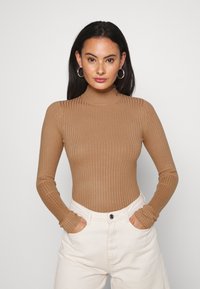 Ribbestrikket brun turtleneck bodysuit med lange ermer og tilpasset design, kombinert med hvite høytlivsbukser.