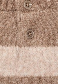 Strickpullover-Detail mit horizontalen Streifen in hellem Beige und Braun, zwei transparenten Knöpfen und strukturiertem Stoff.