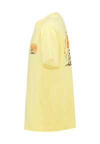 Keltainen puuvillapaita pyöreällä kaula-aukolla, lyhyet hihat, etuosassa ja oikeassa hihassa oransseja ja mustia painokuvia.