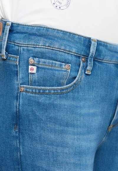 Blå denimjeans med en lätt blekt textur, femfickorsdesign och en liten röd och vit logotagg på framfickan.