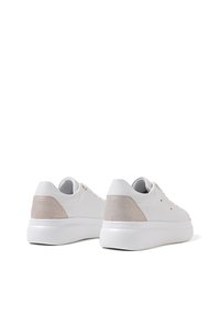 Sneaker bianchi con finitura in pelle liscia, accenti beige testurizzati sul tallone e una suola bianca spessa. Presentano una lace minimale e dettagli ridotti.