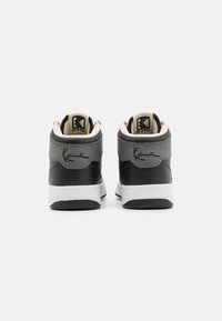 Zapatillas altas que presentan cuero sintético en negro y gris con una entresuela blanca, acentos texturizados y una firma en el talón.