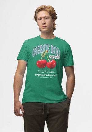 Zelené bavlněné tričko s grafikou třešně a nápisem „CHERRIE ROSA sweet“ a dalšími informacemi o bio produktech v bílé barvě.