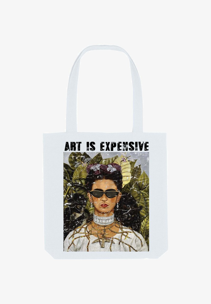 Femme avec des cheveux tressés, portant des lunettes de soleil, des bijoux et un haut blanc avec un motif de branche, devant des feuilles avec le texte "L'ART EST CHER" au-dessus.