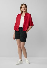 Czerwona lniana koszula, krótki rękaw, zapinana na guziki; w zestawie z czarnymi szortami na elastycznej talii. Bielizna t-shirt v-neck w kolorze białym, białe tenisówki.
