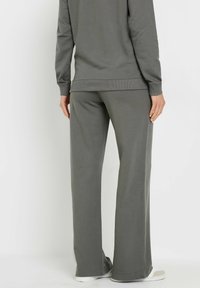 Grijze katoenmix joggingbroek met een relaxte pasvorm, elastische tailleband en subtiele ribbels. Soepele textuur, wijde pijpen en zichtbare zijzakken.