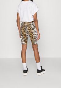 Lepardmönstrade cykelbyxor med sidostreck, åtsittande design och slät tygkvalitet. Bärs med en lös vit T-shirt och sneakers.