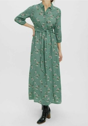 Grünes Maxikleid mit Blumenmuster, durchgehender Knopfleiste, dreiviertel Ärmeln und tailliertem Gürtel. Glatter, leichter Stoff mit weicher Textur.