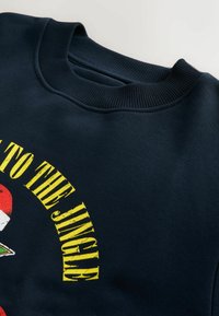 Granatowy sweatshirt z okrągłym dekoltem, z żółtym napisem "JINGLE" oraz elementami graficznymi. Wykonany z miękkiej mieszanki bawełny, z ribbowanym dekoltem.