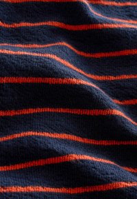 Gestructureerde stof met een donkerblauwe achtergrond en horizontale oranje strepen, met een zachte, geweven textuur en subtiele diepte in het ontwerp.