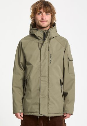 Chaqueta impermeable verde oliva con capucha, cremallera frontal, bolsillos laterales y logo de Volcom. Presenta un corte relajado y una tela texturizada.