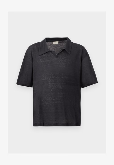 Μαύρο ελαφρύ πλεκτό πόλο με κοντά μανίκια, με διαχυμένο γιακά και χαλαρή εφαρμογή, εμφανιζόμενο σε απλό φωτεινό φόντο.