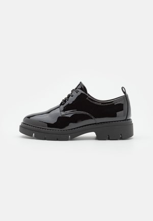 Schwarzer Lackleder-Oxfordschuh mit runder Zehenform, Schnürdesign und klobiger schwarzer Gummisohle mit horizontalem Profil.