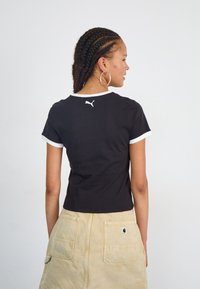 Tricou din bumbac negru cu accente albe, mâneci scurte și gât rotund. Prezintă un mic logo alb Puma pe spate.