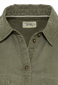 Groen, getextureerd shirt met een button-down kraag, twee knopen bij de halslijn, contrasterende stiksels en een zichtbare merkenlabel aan de binnenkant.