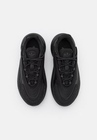 Scarpe sportive nere con un design elegante, materiale sintetico liscio, sovrapposizione testurizzata e lacci tonali. Presentano un marchio prominente sulla linguetta.