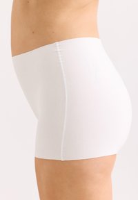 Weiße Baumwollunterwäsche mit nahtlosem Design und Länge bis zur Mitte des Oberschenkels. Weicher Stoff und elastischer Bund für Komfort. Seitenansicht gezeigt.