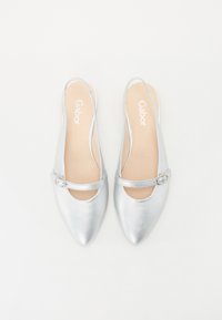 Chaussures en cuir argenté à bride arrière avec un bout pointu, dotées d'une sangle mince et d'une boucle décorative. Texture lisse et brillante.