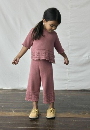 Completo due pezzi lavorato a maglia in rosa soft, composto da un top corto e pantaloni larghi con bordi scallop. Abbinato a scarpe beige.
