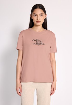Kortærmet, rosenpink bomulds t-shirt med teksten "evolve don’t compete" i mørk skrift centreret på fronten.