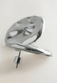 Orecchino in argento metallico con un design astratto arrotondato caratterizzato da curve morbide e chiusura a stud. La superficie riflettente mette in evidenza la texture.