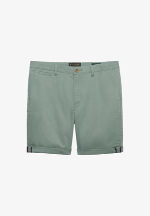 Jasnozielone, bawełniane szorty męskie z zapięciem na guziki, szlufkami na pasek, bocznymi kieszeniami oraz wywiniętymi nogawkami z małym paskowanym detalem.