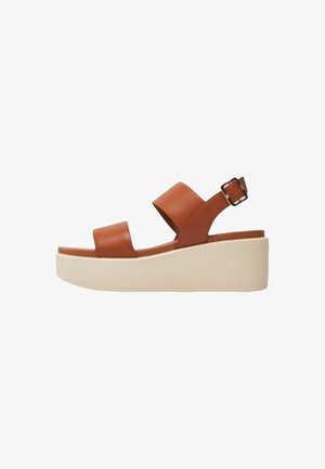 Brown leather wedge sandals with two wide straps, adjustable buckle, and a thick cream-colored platform sole. Smooth texture and modern design.