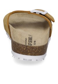 Braune Wildleder-Clogs mit einer Korkzwischensohle und einer weißen Gummisohle; verstellbare silberne Schnalle an einem braunen Riemen. Weiche Innenauskleidung.