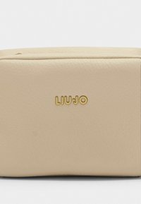 Beige nahktoode, millel on sile tekstuur ja minimalistlik disain. Esiküljel on kuldne "LIU JO" logo.