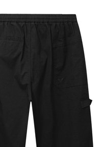 Czarne spodnie z elastycznym pasem, posiadające tylne i boczne kieszenie oraz małe haftowane logo na prawej kieszeni.
