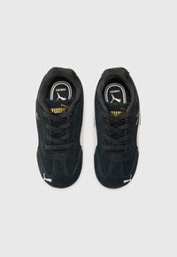Black Puma sneakers with gold accents, featuring a suede texture and laced design, displayed from a top-down perspective on a white background.