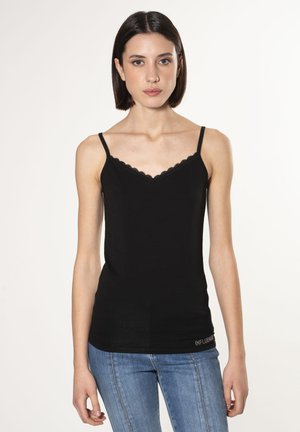Camiseta negra de tirantes con escote en V y encaje, con finos tirantes ajustables. Tejido suave y diseño ajustado, combinada con jeans azules.
