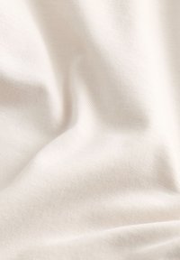 Tessuto beige chiaro, superficie liscia, con un sottile motivo a trama diagonale. La superficie appare leggermente drappeggiata e morbida.