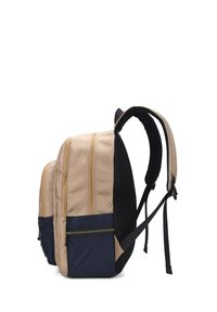 Zaino con tessuto beige e navy, dotato di tre tasche esterne con zip, spallacci in rete imbottiti e un pannello inferiore testurizzato.
