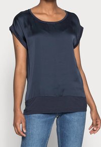 Top corto blu navy a maniche corte realizzato in tessuto morbido, con scollatura rotonda e una vestibilità leggermente rilassata, caratterizzato da un pannello inferiore a tinta unita.