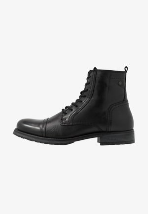 Bota negra de cuero hasta el tobillo con puntera reforzada, cordones en la parte delantera, tacón bajo apilado y lengüeta de tirón en la parte trasera.