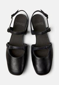 Schwarze Leder-Mary-Jane-Schuhe mit runder Spitze, verstellbarem Schnallenriemen und Ausschnittdetails an der Seite, von oben betrachtet.