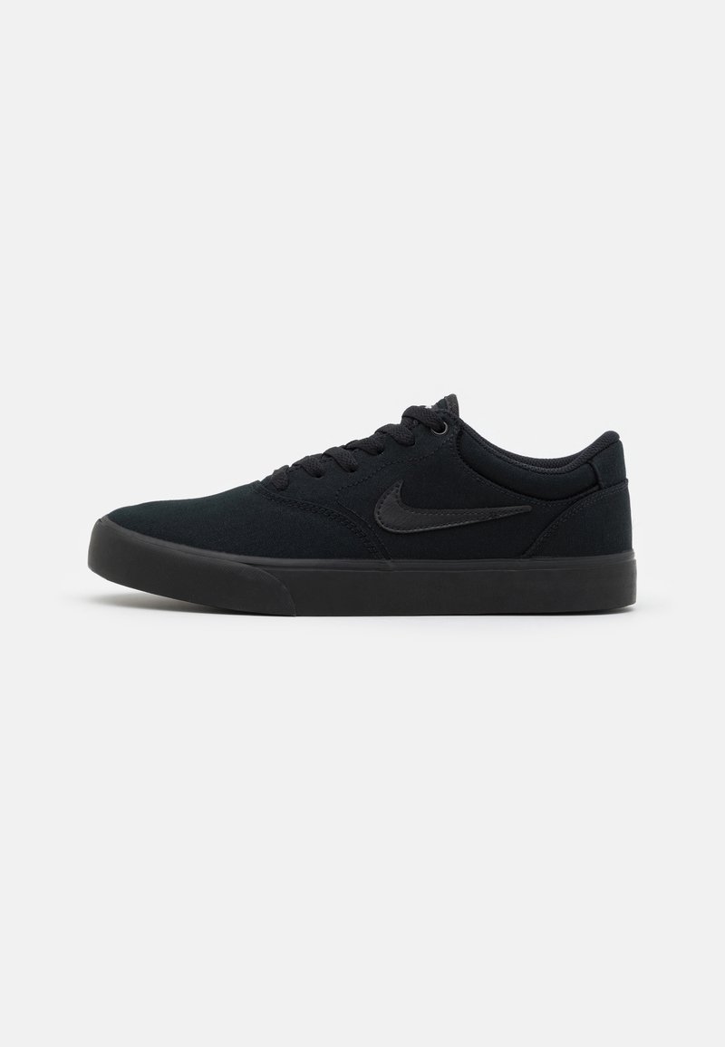 Baskets Nike basses noires en profil latéral avec lacet à l'avant et semelle en caoutchouc sur fond blanc uni.