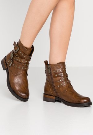 Bottines en cuir marron avec des clous et des boucles en argent, dotées d'un petit talon et d'une fermeture à glissière sur le côté. Texture lisse et bout arrondi.