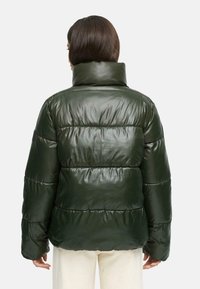 Donker groen pufferjack met een glanzende afwerking, hoge kraag en horizontaal gewatteerd ontwerp. Beschikt over een oversized pasvorm en lange mouwen.