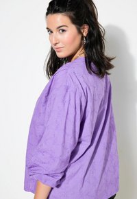 Blusa viola ricamata con una vestibilità morbida, maniche a tre quarti e un motivo testurizzato, con un collo rotondo.