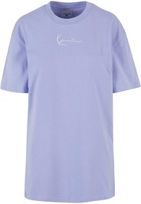 Lys lilla bomulds t-shirt med korte ærmer, rund halsudskæring og hvidt broderet logo på forsiden. Glat tekstur og afslappet pasform.