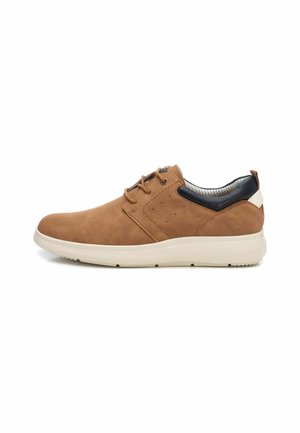 Las sneakers de ante marrón presentan un diseño perforado, acentos en navy contrastantes en el talón y una suela de goma blanca con agarre.