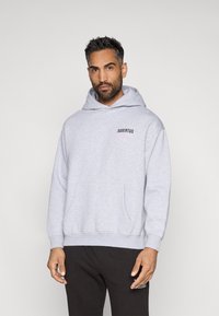 Hallhalli hallhoga, millel on eesmine tasku ja kapuuts nööriga, vasakul rinnal on musta ja roosa värviga prinditud "JUVENTUS". Puuvillane materjal.