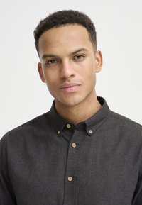 Dark gray button-up shirt with a collar, wooden buttons, textured fabric, and a slim fit design.