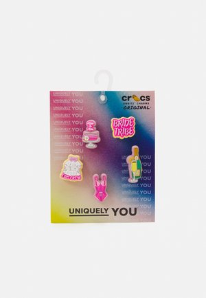 Charmuri Jibbitz de la Crocs pe un fundal în gradient includ un tort roz, textul "Bride Tribe", o rochie albă, un costum de baie roz și o sticlă de șampanie.